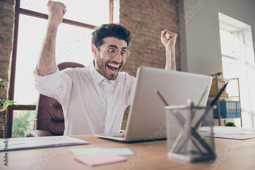 Portrait of crazy surprised middle eastern businessman indian marketer work on computer got notification about successful win project scream yes raise fists sit desktop in loft workstation