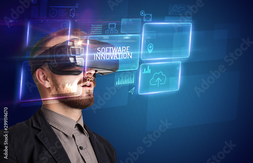 Businessman looking through Virtual Reality glasses with SOFTWARE INNOVATION inscription, new technology concept