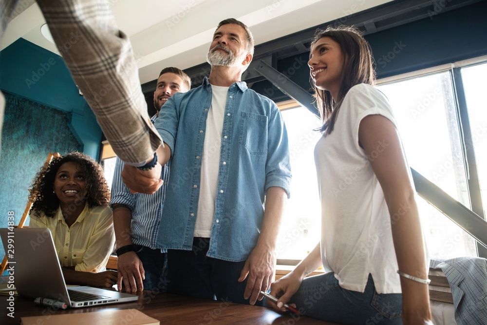 Welcome to our team! Business men in smart casual wear shaking hands while working in the creative office. Welcome to our team! Business men in smart casual wear shaking hands while working in the creative office.