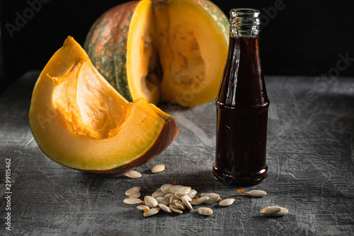 in the bottle  dark pumpkin oil is next to the cut pumpkin and seeds. Horizontal orientation.