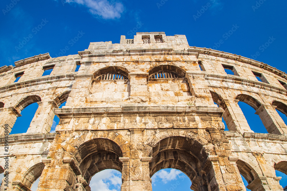 Monumental ancient Roman arena in Pula, Istria, Croatia, historic amphitheater wide angle view of high walls on blue sky background