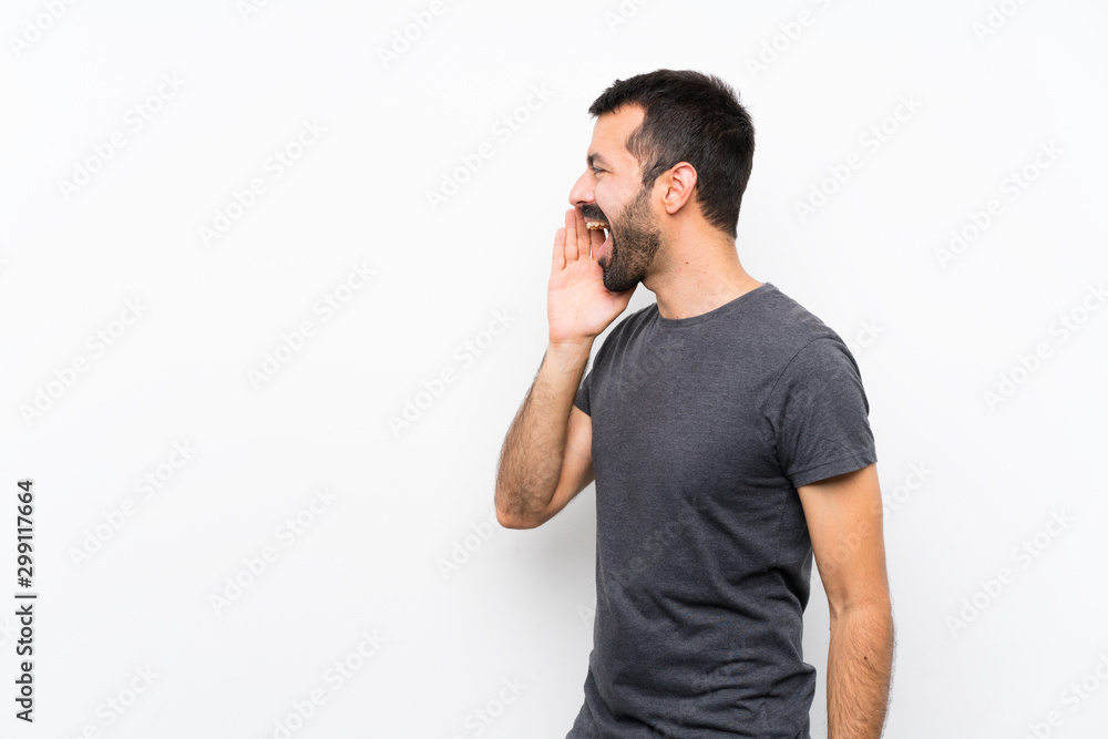 Young handsome man over isolated white background shouting with mouth wide open to the lateral Young handsome man over isolated white background shouting with mouth wide open to the lateral