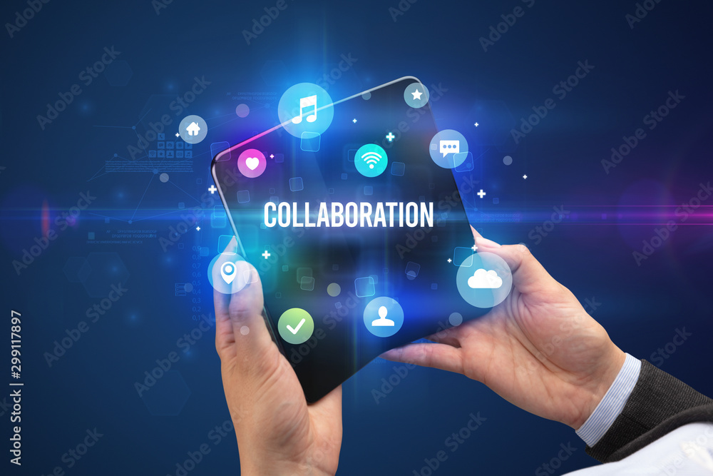Businessman holding a foldable smartphone with COLLABORATION inscription, social media concept Businessman holding a foldable smartphone with COLLABORATION inscription, social media concept
