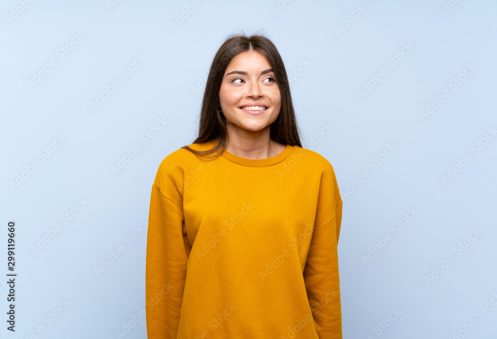 Caucasian young woman over isolated blue wall laughing and looking up Caucasian young woman over isolated blue wall laughing and looking up