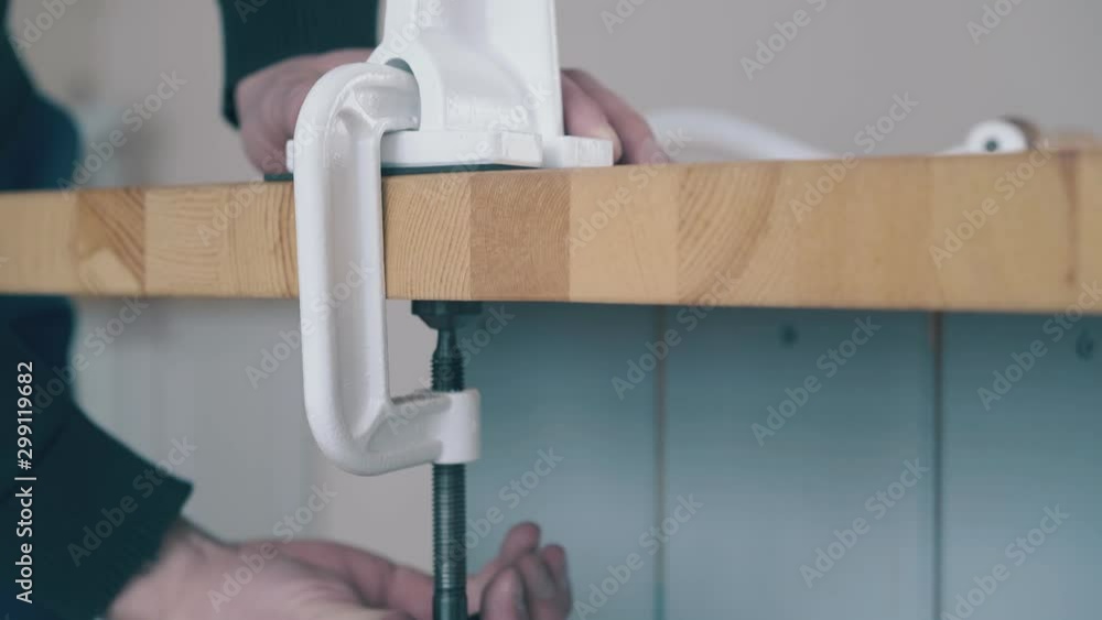 man in black puts fixing detail to install home four mill on modern wooden table in kitchen closeup man in black puts fixing detail to install home four mill on modern wooden table in kitchen closeup