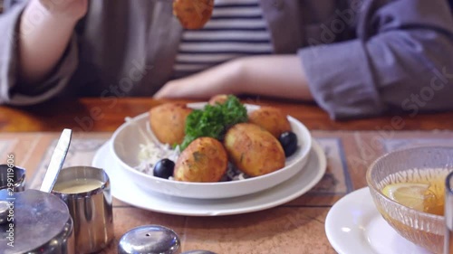 Woman in cropped view eating salted cod food, Pasteis de Bacalhau, Bacalao, Bacallao, delicious Portuguese dishes meal in Macau restaurant, lifestyle.
