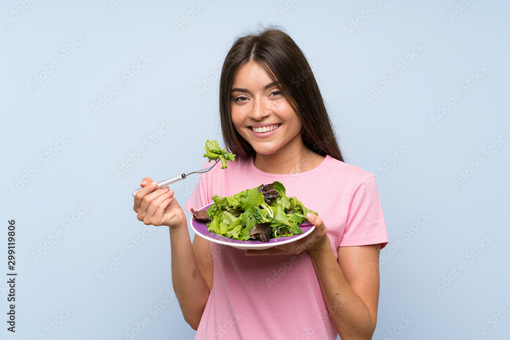 Young woman with salad over isolated blue background Young woman with salad over isolated blue background