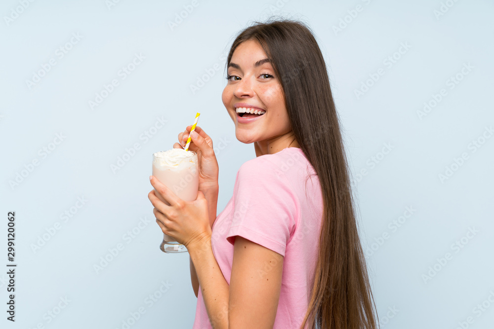 Young woman with strawberry milkshake over isolated blue background Young woman with strawberry milkshake over isolated blue background
