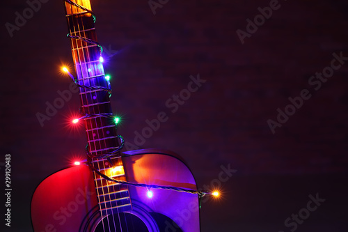 Valokuva Acoustic guitar with Christmas lights against dark background