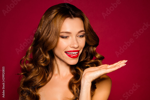 Close-up portrait of her she nice charming attractive cheerful wavy-haired girl holding on palm invisible thing advert isolated bright vivid shine vibrant red maroon burgundy marsala color background