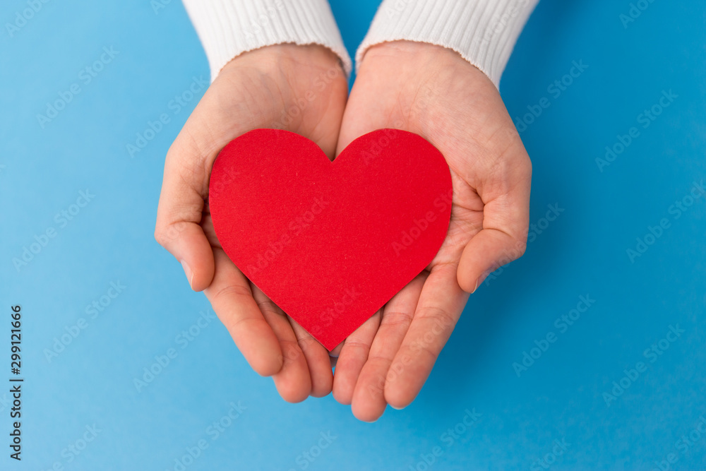 love, health and valentine's day concept - hands holding red heart shape on blue background love, health and valentine's day concept - hands holding red heart shape on blue background