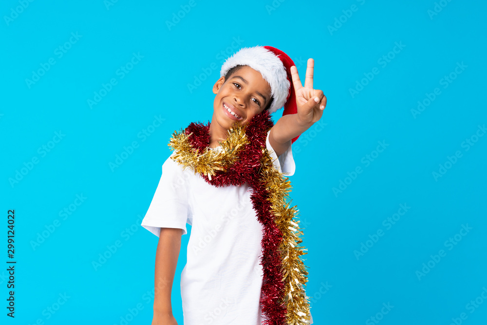 Obraz premium African American boy with christmas hat smiling and showing victory sign