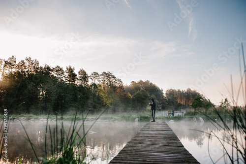 Wallpaper Mural Fisherman with fishing rod on bridge. Sunrise. Fishing for pike, perch, crucian carp. Fog, grass, trees against the backdrop of lakes, nature. Fishing background. Misty morning. the wild nature. river Torontodigital.ca