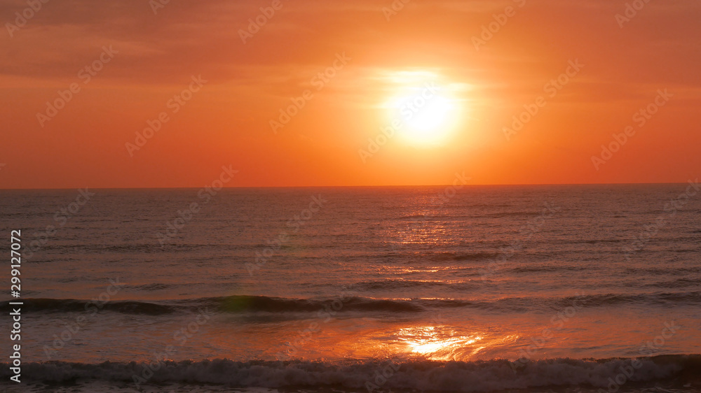 Sunrise over the sea. The sun is showing and coloring the sky in golden yellow. Bright path to the shore.