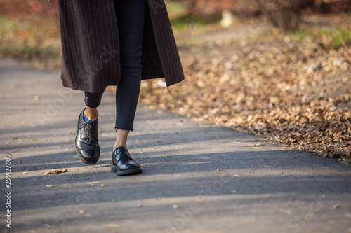 Closeup legs fashionable woman wear black shoes and brown coat. Stylish fall outfit