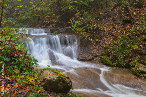 Wasserfall  im Herbst im Wald mit Nebel