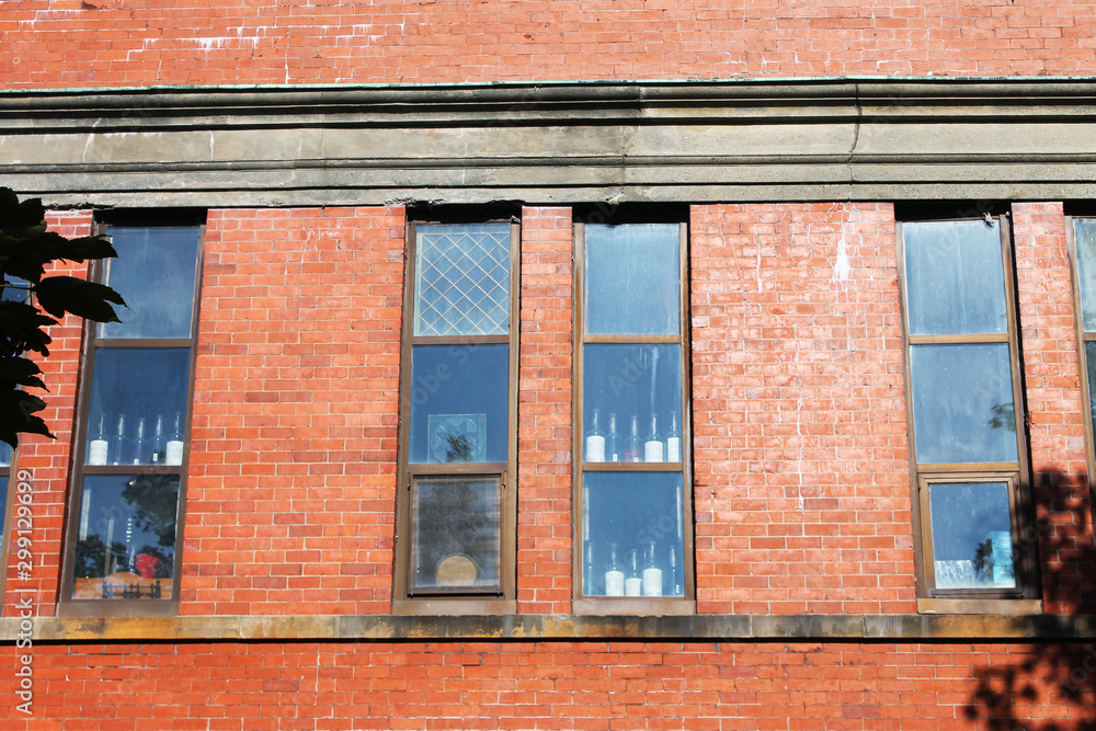 Windows in wall of old red brick building. Wine bottles are visible through the glass. Windows in wall of old red brick building. Wine bottles are visible through the glass.