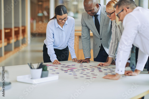 Diverse businesspeople solving a jigsaw puzzle together in an of