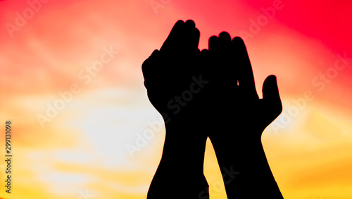 Silhouette image of praying hand of muslim on golden sky background in the evening