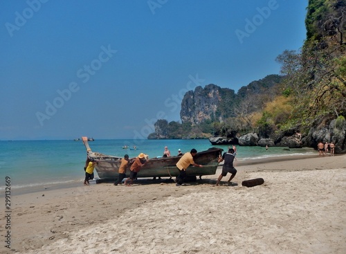 fischermen taking a boat out of the sea in thailand