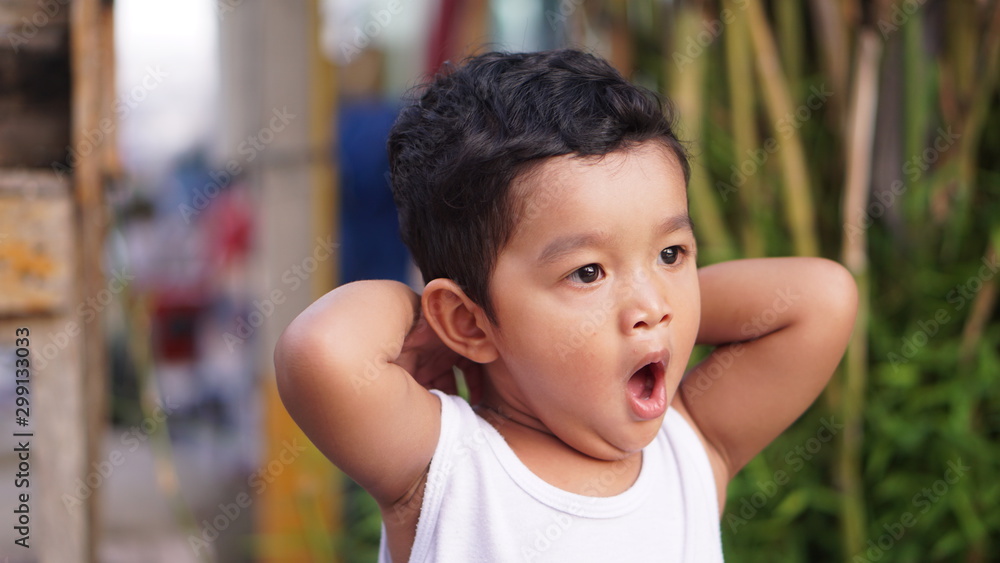 Asian boy sitting near the water front, pretending to be sleepy and yawning with a wide mouth. Asian boy sitting near the water front, pretending to be sleepy and yawning with a wide mouth.