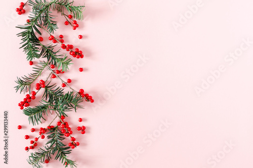 Christmas modern composition. Fir tree branches, red berries, Xmas decorations on pastel pink background. Christmas, New Year, winter concept. Flat lay, top view, copy space
