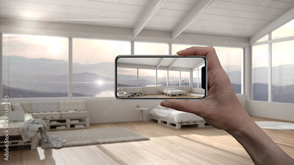 Hand holding smart phone, AR application, simulate furniture and interior design products in real home, architect designer concept, blur background, modern diy bedroom with pallet bed Hand holding smart phone, AR application, simulate furniture and interior design products in real home, architect designer concept, blur background, modern diy bedroom with pallet bed