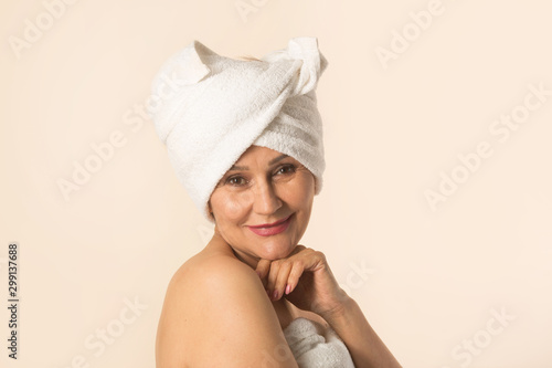 stylish beautiful aged woman in a white towel on a beige background