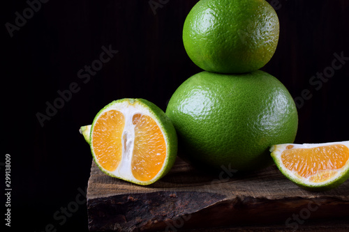 Green mandarins cut in halves and segments and whole sweetie on a wooden table