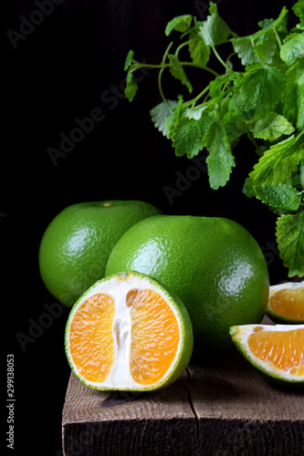 Green mandarins cut in halves and segments and whole sweetie on a wooden table