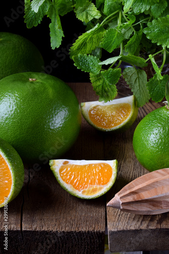 Green mandarins cut in halves and segments and whole sweetie on a wooden table