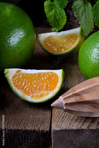 Green mandarins cut in halves and segments and whole sweetie on a wooden table
