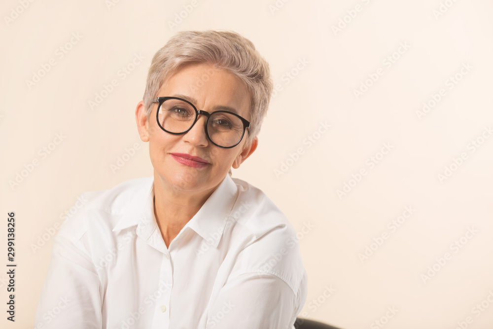 stylish beautiful woman with a short haircut, in a white shirt on a beige background