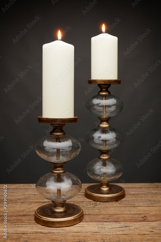 2 glass candle holders and glowing candles, shot on a wooden table