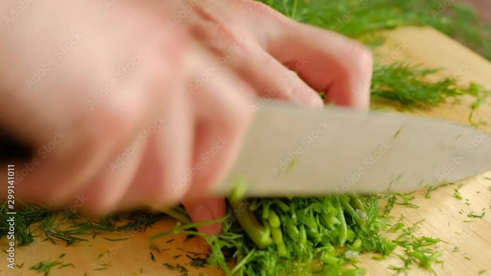 Cutting fresh dill on a cutting board with knife. Green healthy ingredient, bunch. Cutting fresh dill on a cutting board with knife. Green healthy ingredient, bunch.