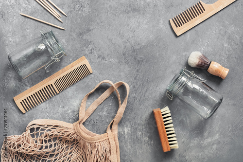 Eco friendly objects. Cotton bag, glass jar, wooden comb, wooden shaving brush, cuticle pusher, brush on a gray background. Zero waste. Flat lay, top view.