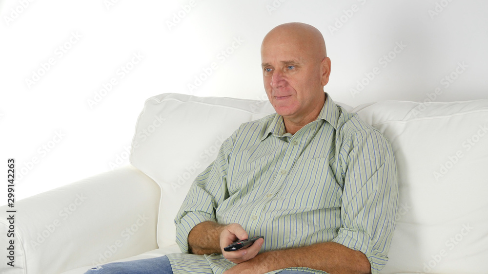 Image with a Person Sitting on the Sofa and Changing TV Program with Remote Image with a Person Sitting on the Sofa and Changing TV Program with Remote
