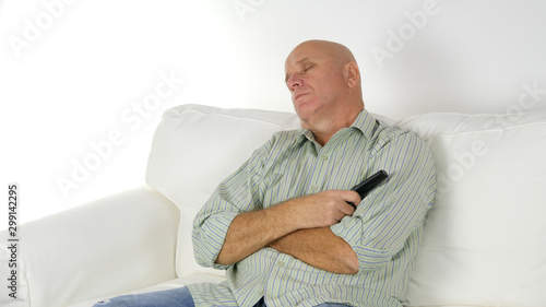 Image with a Tired Person Sleeping with TV Remote in Hand on the Sofa