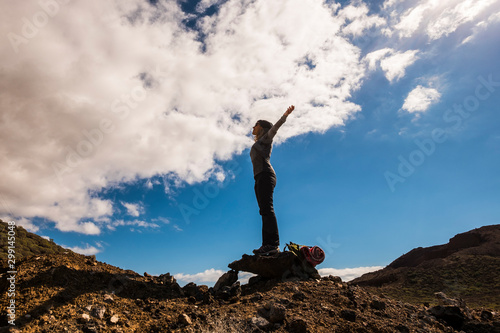 People having success in healthy outdoor leisure activity - trekking and adventure on mountains - standing woman with open arms enjoying freedom - blue sky in background