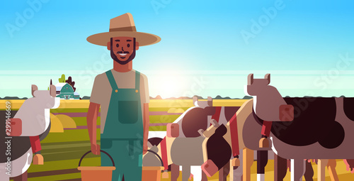 milkman holding buckets with fresh milk farmer standing near herd of cows grazing on grassy field eco farming husbandry concept sunset landscape background closeup horizontal portrait vector