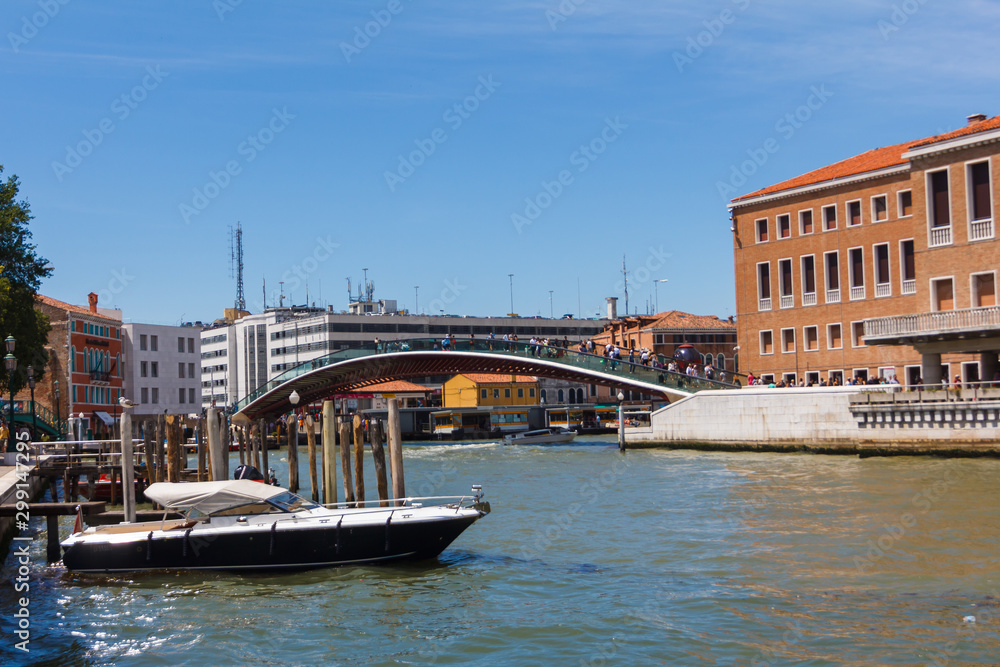 Grand Canal in Venice with boats and gandules docket motor boat near the bridge. Colorful residential house and small bridges cross the canal.