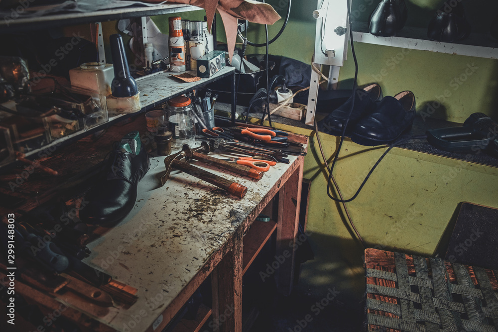 Workplace of cobbler with necessary tools on it at dark workshop.