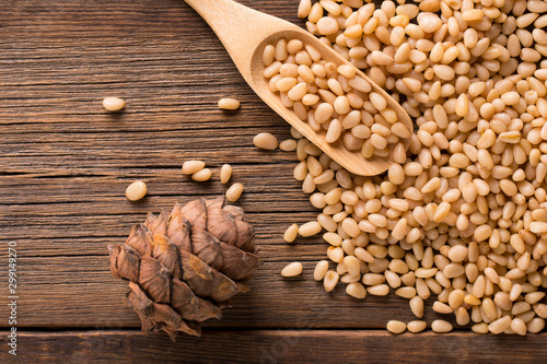 Cedar cone close-up. Peeled pine nuts in a bag on a wooden background.