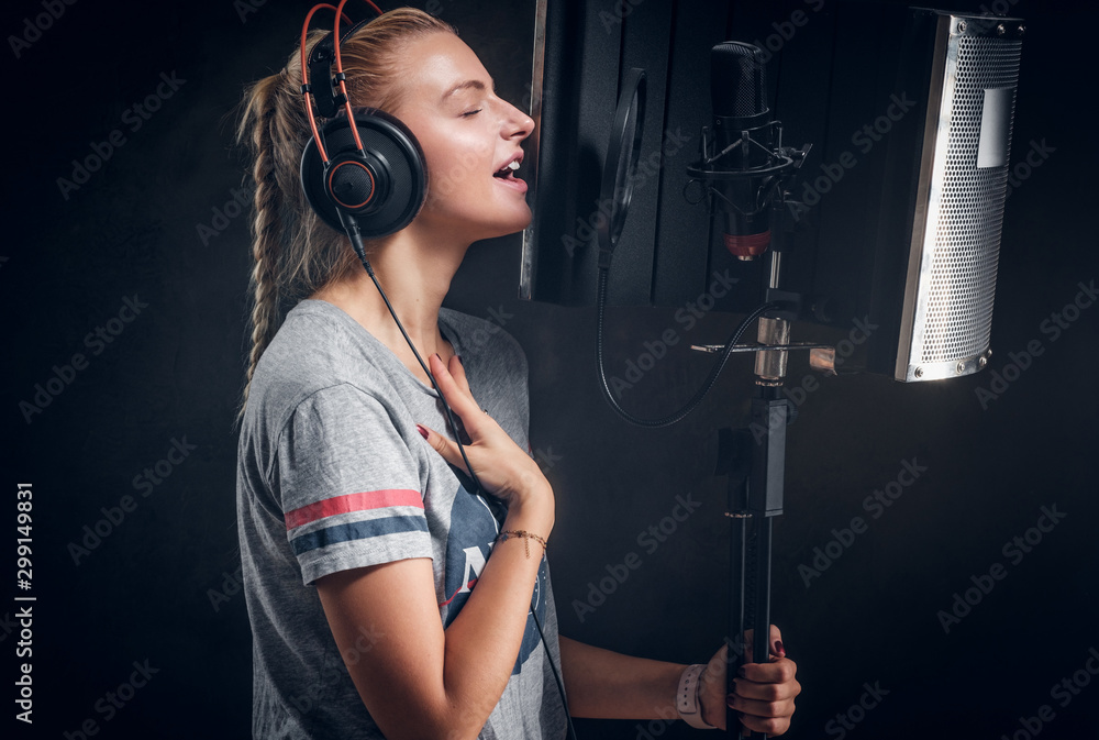 Focused emotional girl is singing her new passion song for recording at studio.