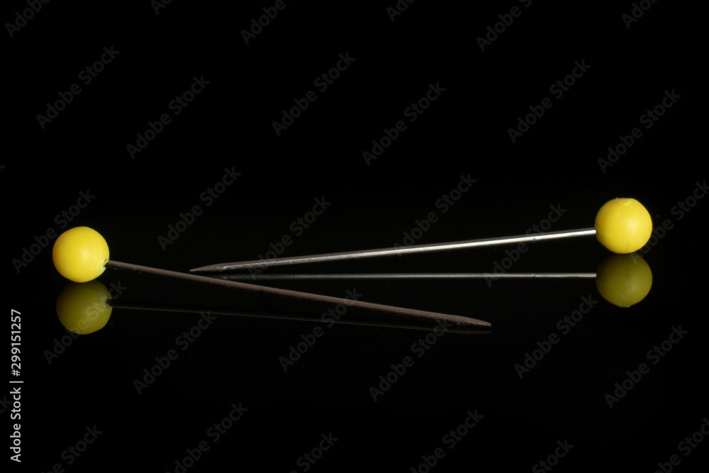 Group of two whole haberdashery item yellow needles isolated on black glass Group of two whole haberdashery item yellow needles isolated on black glass