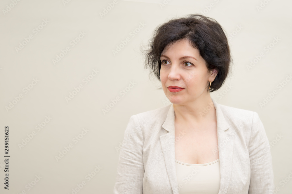 Obraz premium Pretty business woman, successful confidence portrait with copy space. Attractive middle aged woman in business suit against concrete beige wall.