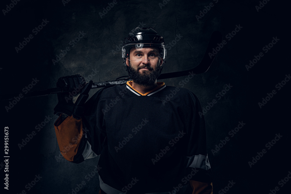 Portrait of brutal bearded man in hockey player uniform at dark photo studio. Portrait of brutal bearded man in hockey player uniform at dark photo studio.