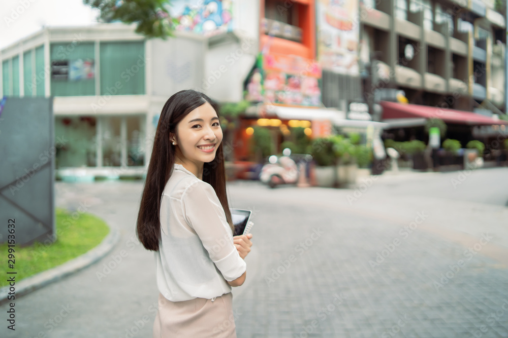 Young Asian Chinese business woman smiling and use digital tablet computer outdoor near office building,She has long black hair ,happiness girl with Summer sunny lifestyle fashion portrait on street Young Asian Chinese business woman smiling and use digital tablet computer outdoor near office building,She has long black hair ,happiness girl with Summer sunny lifestyle fashion portrait on street