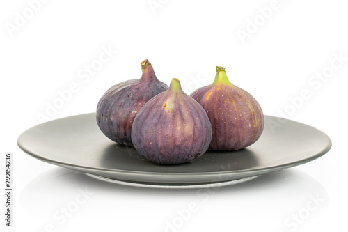 Group of three whole fresh purple fig on gray ceramic plate isolated on white background