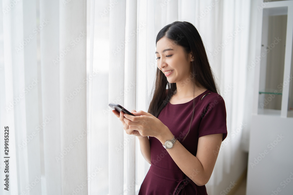 Young Asian woman serving internet she looking a smartphone,messaging and smiling while sitting on carpet near sofa at home,lifestyle,Social networks for sale product, shopping, fashion asia people Young Asian woman serving internet she looking a smartphone,messaging and smiling while sitting on carpet near sofa at home,lifestyle,Social networks for sale product, shopping, fashion asia people